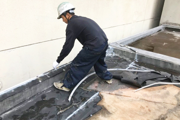 陸屋根の古くなった防水層を剥がす様子